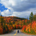 motorcycler riding on a road surrounded by fall foliage