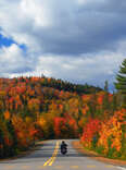 motorcycler riding on a road surrounded by fall foliage
