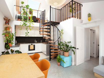The quintessential London Airbnb Kitchen, complete with a set of stairs leading to a loft space and plenty of greenery.