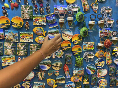 Hand reaching for Goa tourism magnets 