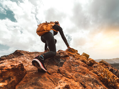 woman climbs mountaintop
