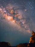 Person stargazing on edge of a canyon