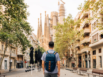 A young man with backpack looking at Sagrada Familia in Barcelona