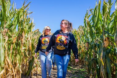two women walking through corn maze