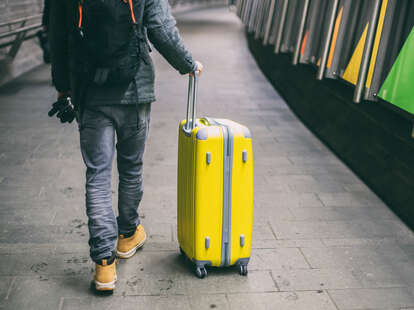 Close up of young man walking with luggage