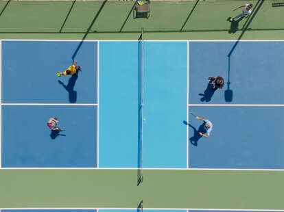Top down drone shot of a group of people playing a doubles game of pickleball