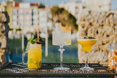 trio of colorful cocktails with ocean backdrop