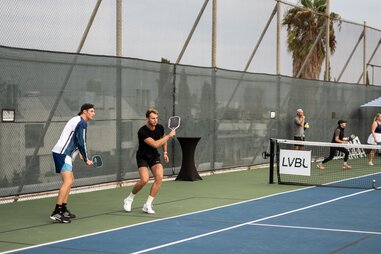 two men playing pickleball at an outdoor court