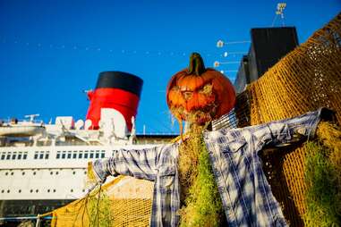 jack-o-lantern scarecrow in front of queen mary ship