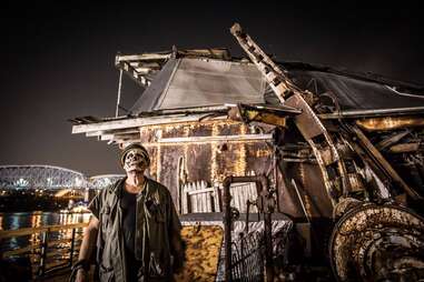 man with skeleton face standing in front of abandoned uss nightmare