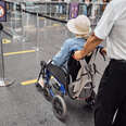 Back view of an airport male employee transporting a disabled female traveler to a plane.