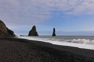 two basalt columns on a black sand beach in iceland