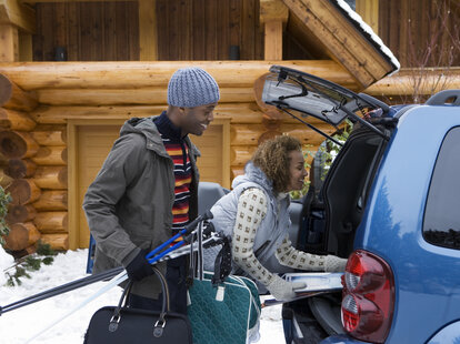 Couple packing trunk in the snow during winter holidays.