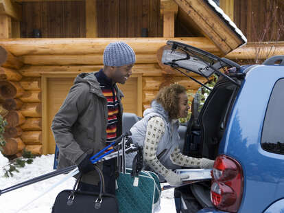 Couple packing trunk in the snow during winter holidays. 