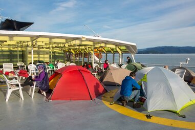 people pitching colorful tents onboard alaska state ferry