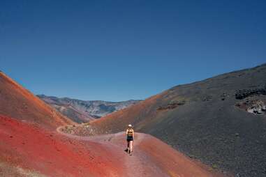 woman hiking through red terrain of haleakalā national park