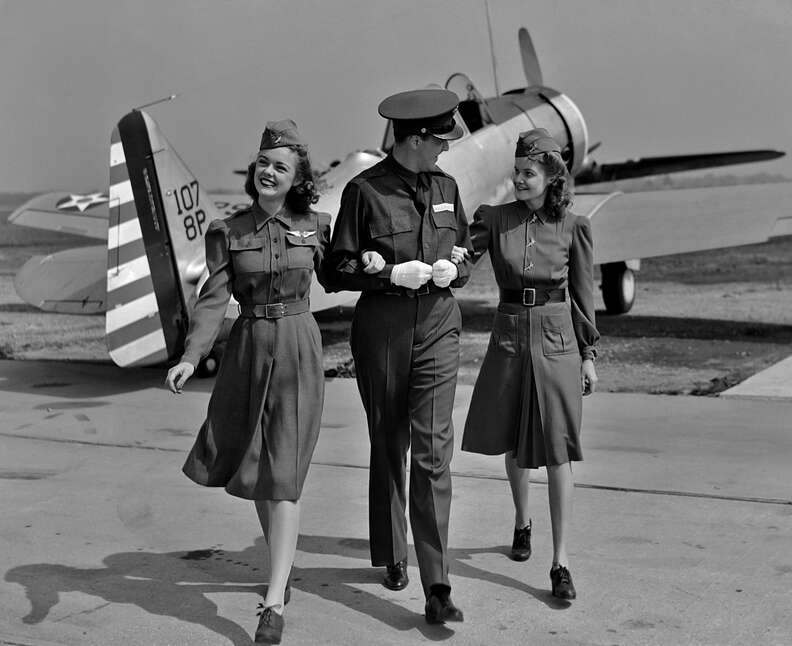 Three flight attendants with airplane in 1940s