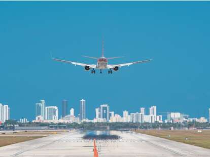 Airplane about to land at Miami International Airport with Downtown Miami skyline. 