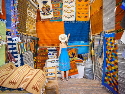 a woman looking at colorful rugs in Mexico 