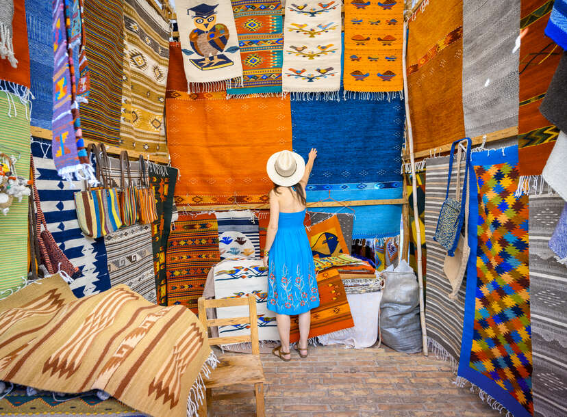 a woman looking at colorful rugs in Mexico 