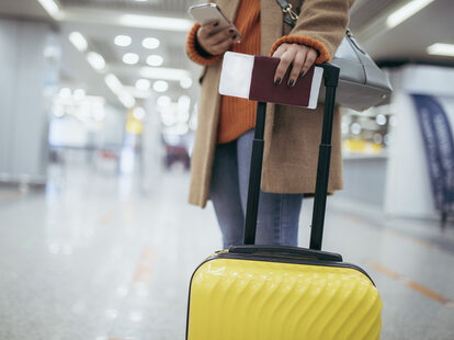 Young woman at the airport with passport and luggage in hand