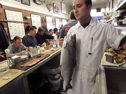 Kevin Santimino holds a fresh king salmon before cleaning it at the Swan Oyster Depot
