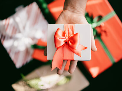Man holding a wrapped gift box on his palm.