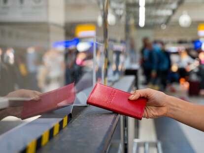 Faceless woman giving her passport at the airport check-in counter.