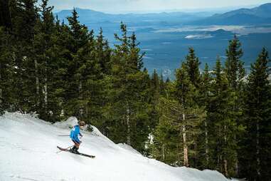 person skiing down a mountain with forest in the background