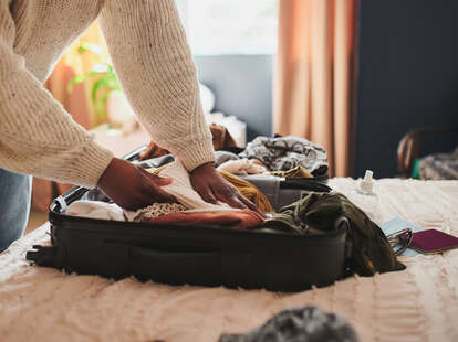 Woman packing her things into a suitcase at home before traveling