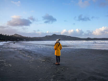 A woman standing on the coast of Vancouver Island looking at mountains.