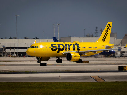A Spirit Airlines airplane taxis at Fort Lauderdale-Hollywood International Airport (FLL) in Fort Lauderdale, Florida under a dark and stormy sky.