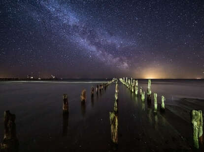 The Milky Way in the night sky over a broken pier in Kolka parish, Latvia