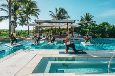 people doing yoga on floating mats in a pool 