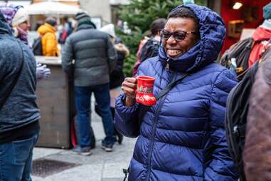 smiling woman at a christmas market with mulled wine