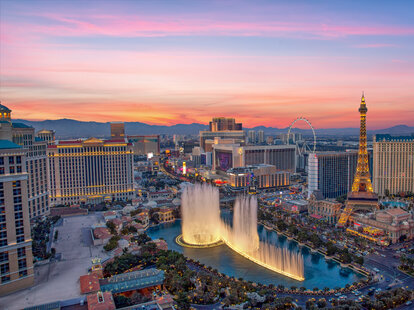 Illuminated view Bellagio Hotel fountains and Las Vegas strip at sunset.