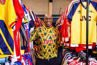 man posing with variety of football jerseys 