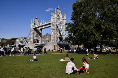 tourists relaxing in potters fields park in front of tower bridge