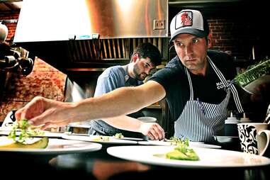 chefs at roost plating dishes in the kitchen