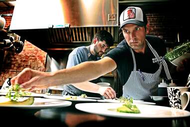 chefs at roost plating dishes in the kitchen 