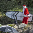 Santa carrying a surfboard