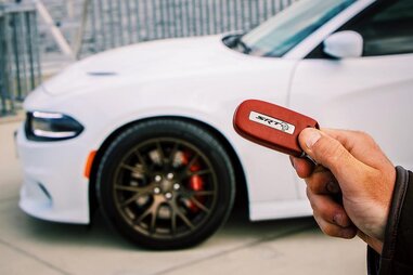driver holding car key with rental car in background
