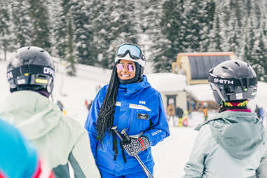 EDGE Outdoors founder, Annette Diggs, holding ski poles, talking to two women