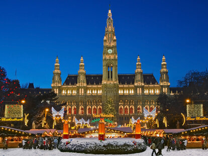 A Vienna Christmas Market at night, after light snowfall, with twinkling lights.