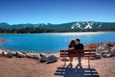 kiss at Big Bear lake in front of snowy mountains