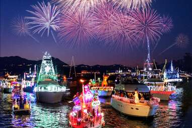 boats decorated for christmas, float on the water, with fireworks in the sky
