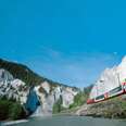 glacier express train, rolling by blue alpine lake, in switzerland
