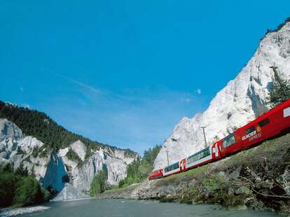 glacier express train, rolling by blue alpine lake, in switzerland