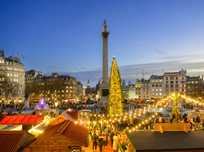 Trafalgar Square Christmas tree and festive market with Nelson&rsquo;s Column and Big Ben on shortest day of the year the winter solstice.