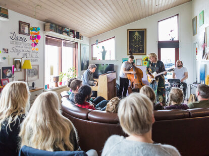 a room full of people listening to a concert held inside a private home on the faroe islands